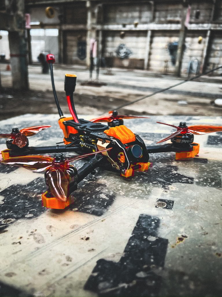 Mario 5 analog 5-inch FPV drone with Caddx Ratel 2 camera, SpeedyBee TX1600 VTX, and bright orange 3D printed parts, built for Killhouse Academy FPV school in Ukraine from Norial FPV.